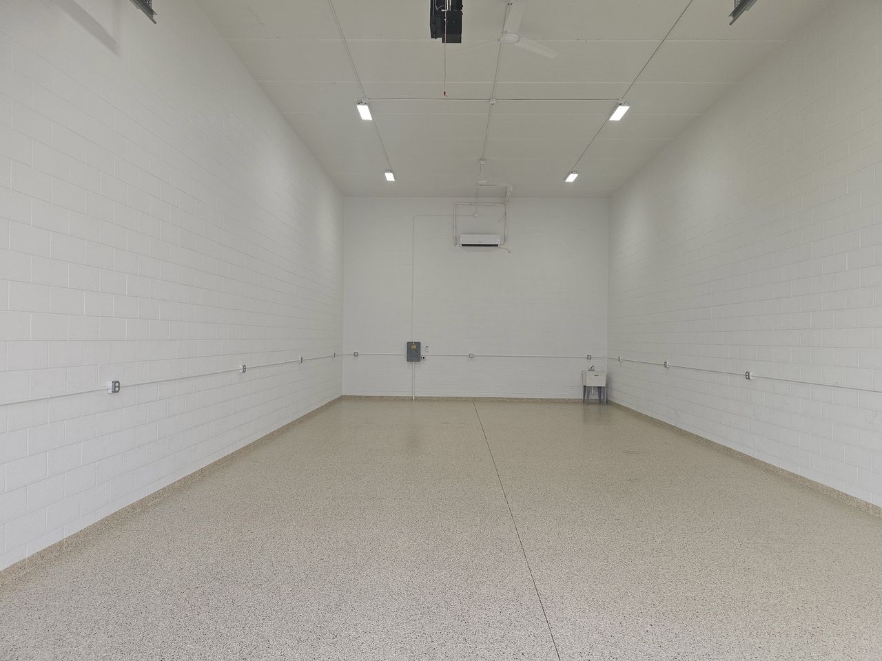 Empty garage condo interior with epoxy floor, high ceiling, LED lighting and ceiling fans