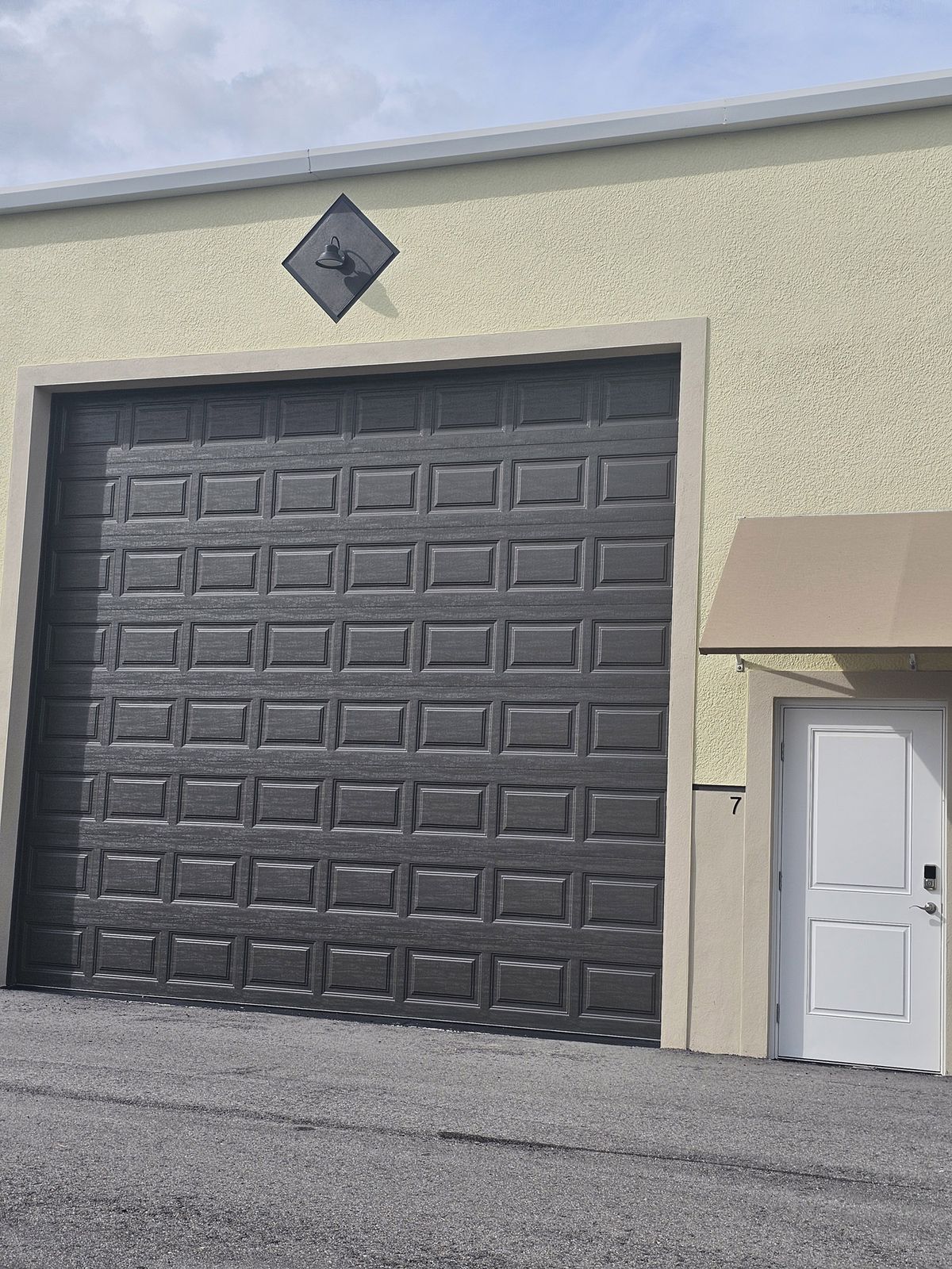 Garage condo unit with dark overhead door and white entry door